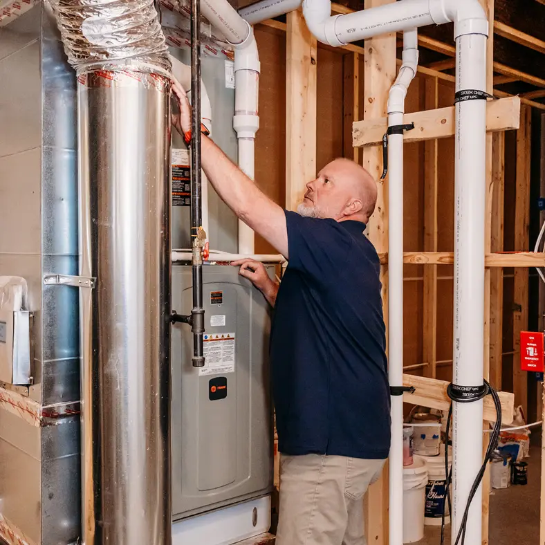 Dave's Heating and Air technician inspecting a high-efficiency Trane furnace and ductwork in Northern Virginia.