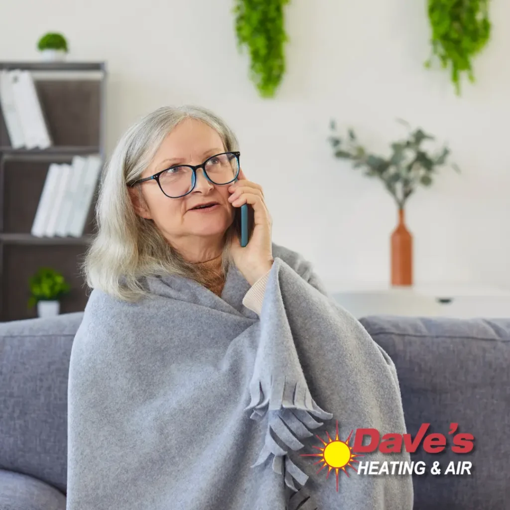 Senior woman wrapped in a warm blanket calling Dave's Heating and Air for emergency furnace repair in Northern Virginia.