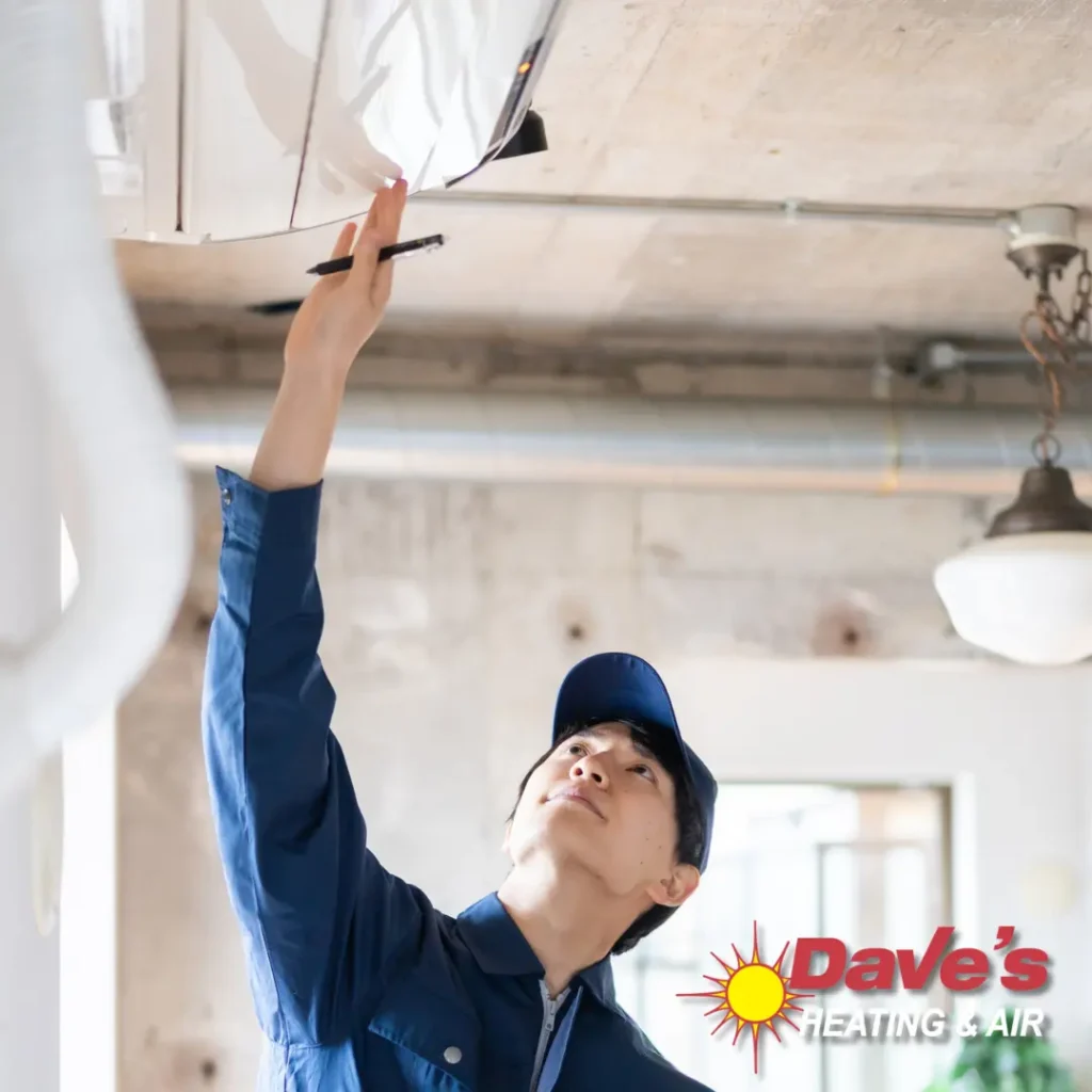 Dave's Heating and Air technician reaching up to inspect a wall-mounted ductless mini-split air conditioner in Northern Virginia.
