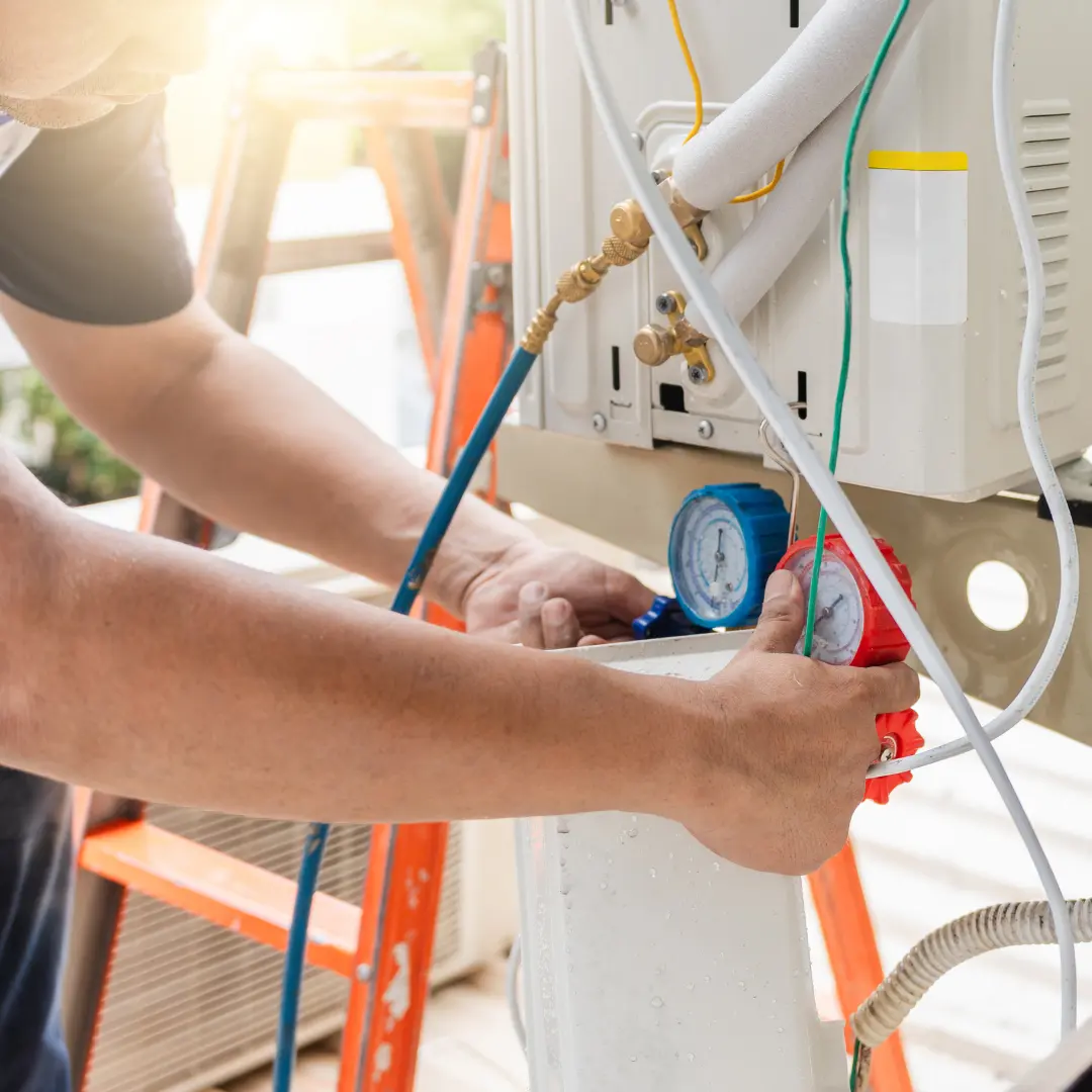 HVAC technician connecting manifold pressure gauges to an outdoor ductless mini-split condenser unit in Northern Virginia.